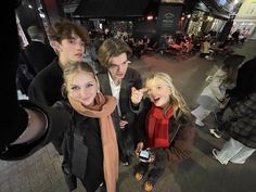 a group of young people standing next to each other on a city street at night