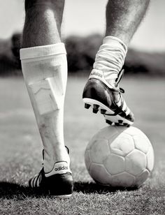 a person standing on top of a soccer ball with their feet on the ball while wearing socks