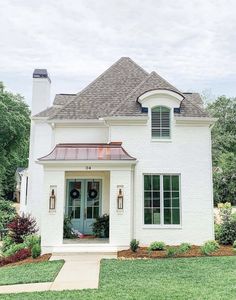 a white brick house with green shutters on the front door and windows in the side