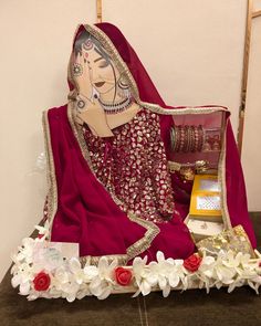 a woman in a red sari sitting on a table with white flowers and other items