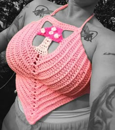 a woman wearing a pink crocheted bag with a flower on it