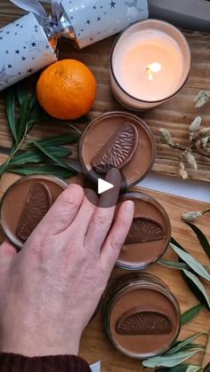 a person is decorating some chocolates on a table with oranges and candles