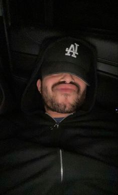 a man wearing a los angeles dodgers hat in the back of a car at night