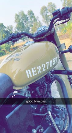 a yellow motorcycle parked on the side of a road next to a field and trees