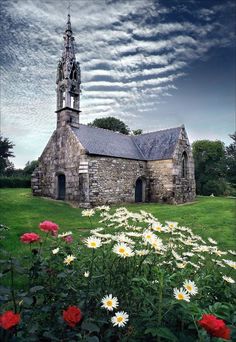 an old stone church surrounded by wildflowers and other flowers in the foreground