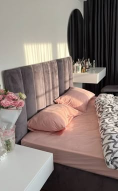 a bed with pink sheets and pillows in a room