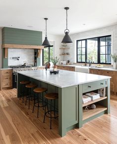 a large kitchen with wooden floors and green cabinets