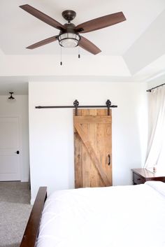 a bed room with a neatly made bed and a sliding door in the wall next to it