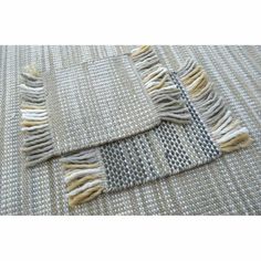 two pieces of woven fabric with fringes on the bottom and one piece in grey, white