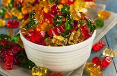 a bowl filled with gummy bears sitting on top of a table next to napkins