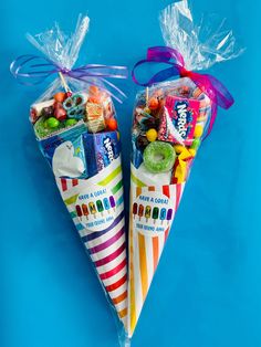 two candy cones wrapped in cellophane and tied with ribbons on a blue background