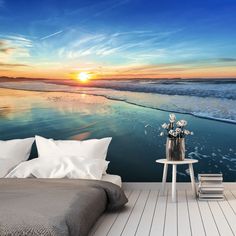 a bedroom scene with the sun setting over the ocean wallpaper and a bed in front of it