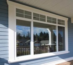 an open window on the side of a house with blue siding and wood flooring