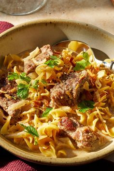 a bowl filled with pasta and meat on top of a table