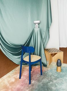 a blue chair sitting on top of a rug next to a wooden table and stool