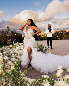 a woman in a white dress standing next to flowers