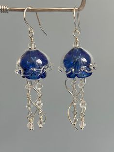 a pair of earrings with blue glass beads hanging from silver earwires on a hook