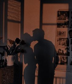 the shadow of a man and woman kissing in front of a window