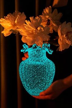 a person holding a glowing vase with flowers in it