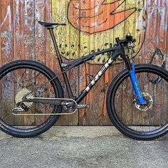 a mountain bike parked in front of a wooden wall with graffiti on it's side