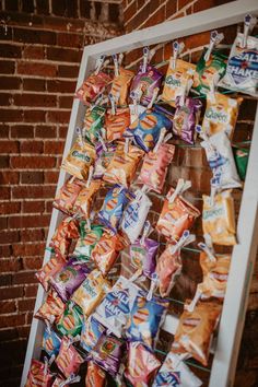 an assortment of snacks are hanging on a rack in front of a brick wall and door