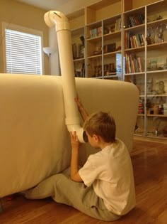 a young boy sitting on the floor with a large white object in front of him