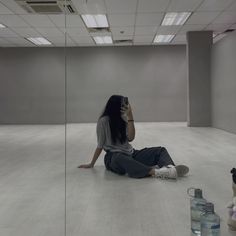 a woman sitting on the floor taking a selfie in an empty room with stuffed animals