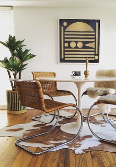 two chairs sitting at a table with a cow hide rug on the floor next to it