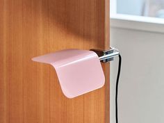 a pink light is attached to a wooden door with a metal hook on the side