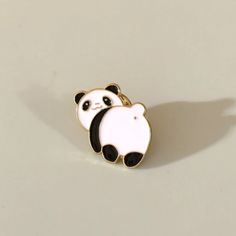 a white and black panda bear pin sitting on top of a table next to a shadow