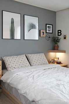 a bed with white sheets and pillows in a bedroom next to two pictures on the wall