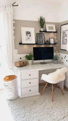 a desk with a computer on top of it in front of a window and some pictures