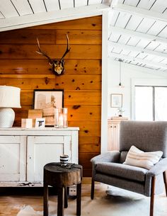 a living room with wood paneling and an antler's head on the wall