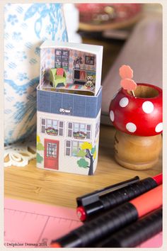 a small doll house sitting on top of a table next to a pen and marker