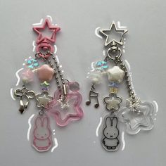 two key chains with charms attached to them on a white surface, one has a rabbit and the other is a star