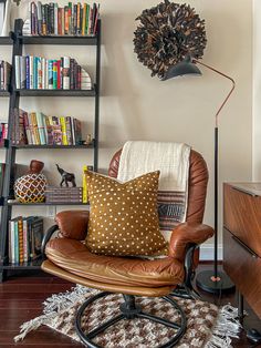 a brown chair sitting in front of a book shelf filled with books