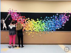 two girls are standing in front of a large painting with colorful bubbles on the wall