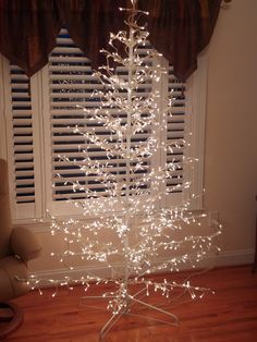 a lighted christmas tree in front of a window