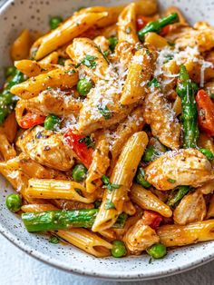 pasta with chicken, asparagus and parmesan cheese in a white bowl