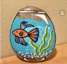 a painted glass fish bowl sitting on top of a wooden table next to a wall