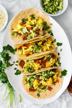 three breakfast tacos on a white plate