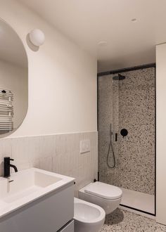 a bathroom with a sink, toilet and shower stall in the background is a large mirror