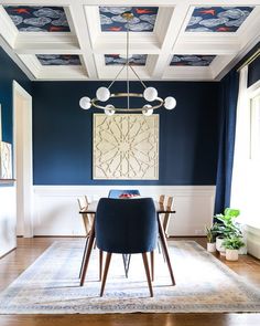 a dining room with blue walls and white trimmings on the ceiling, along with an area rug