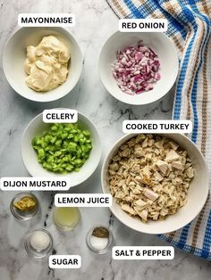 the ingredients for chicken salad laid out in bowls on a marble counter top, including onions, celery, lemon juice and mayo