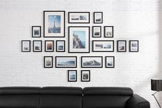 a black leather couch sitting in front of a white brick wall with pictures on it