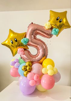 the number five balloon arrangement is filled with helium balloons and gold star shaped foil balloons