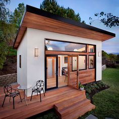 a small white house with wooden steps leading up to the front door and patio area