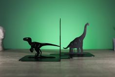 two paper cut dinosaurs are standing next to each other on the floor in front of a green background