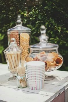 an assortment of desserts and drinks on a white table in front of some trees