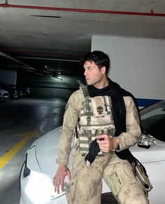 a man sitting on top of a white car in a parking garage